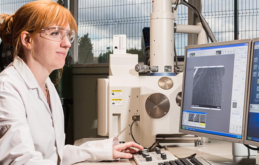 Red haired woman in a white lab coat at a computer