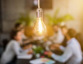 lightbulb in front of out of focus group of people at table