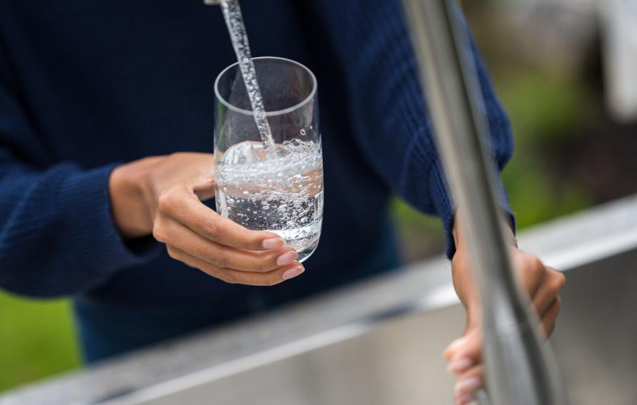 Woman's hands filling glass with water stock photo