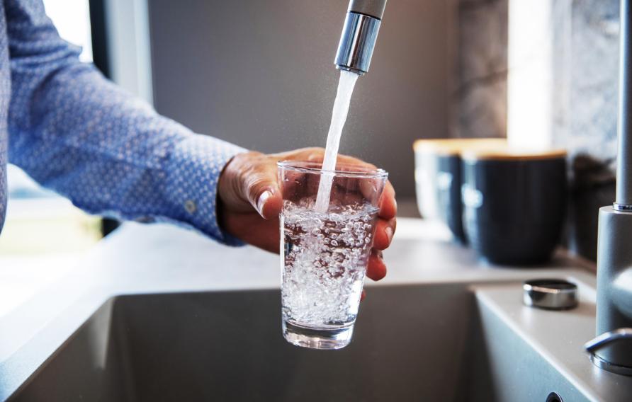 man filling glass of water from faucet