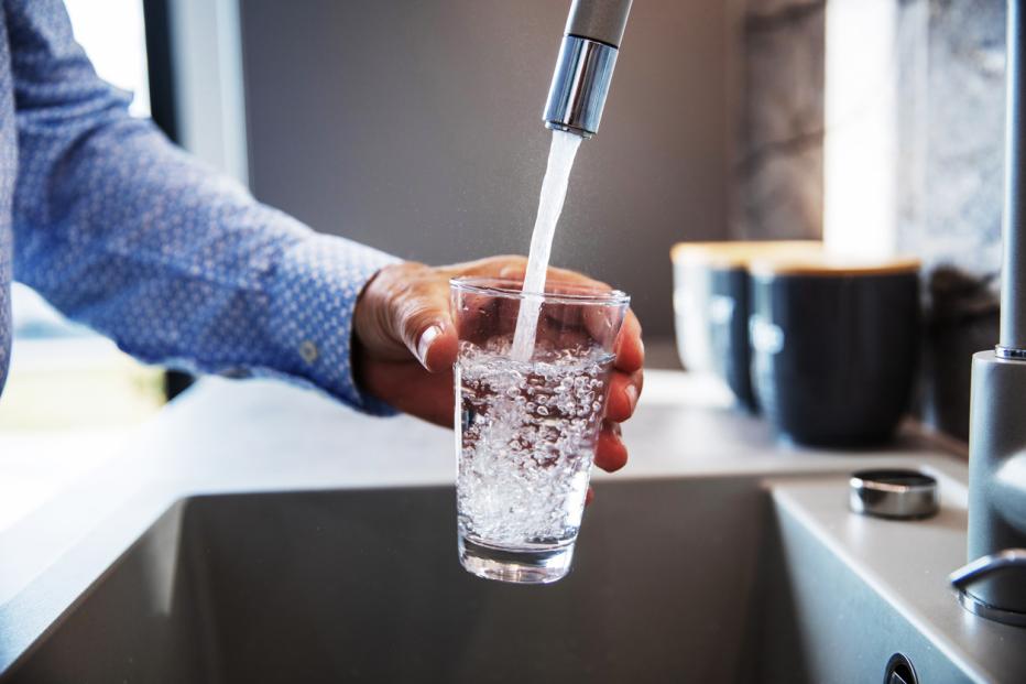 man filling glass of water from faucet