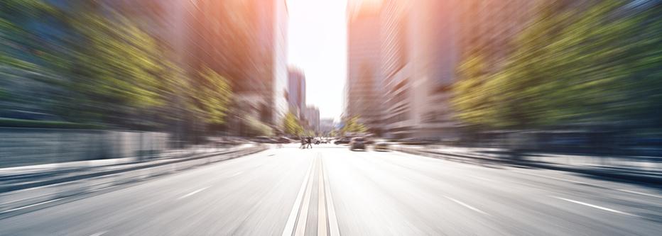 Blurred image of a road facing toward a downtown with office buildings