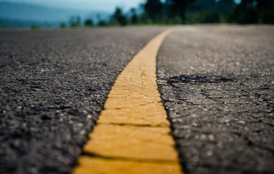 Asphalt highway with yellow line detail on road background