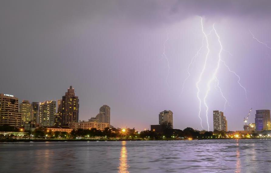 Cityscape with purple overcast sky and lightning striking over water