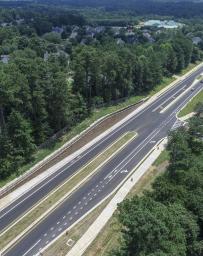 Aerial view of a two lane highway surrounded by green trees on both sides