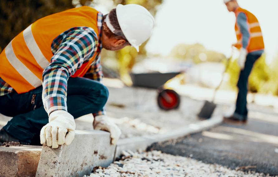 Men in orange and white PPE perform road construction