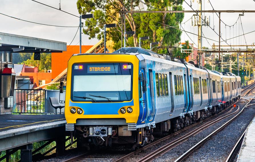 Yellow and blue train on tracks rolling into a station